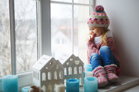 Niña en ventana mirando la nieve