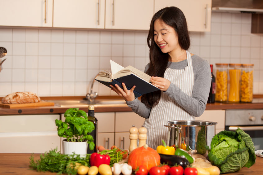 Mujer leyendo y cocinando
