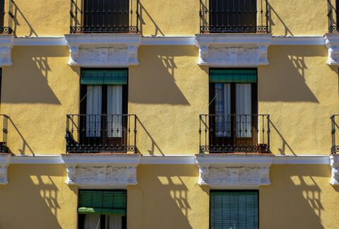 Fachada amarilla de un edificio de viviendas con balcones, ilustrando el precio de la vivienda en España en 2026