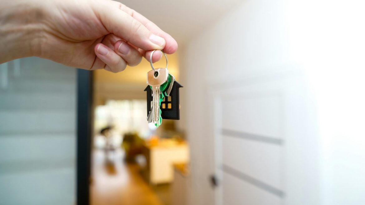Propietario con las llaves en la puerta de su piso, dudando entre vender o alquilar piso en 2026